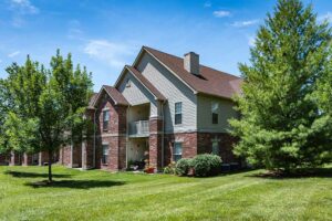 A two-story apartment complex at The Waterways of Lake Saint Louis with private patios and balconies looking towards a green grassy area.