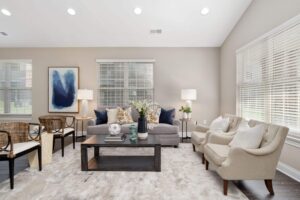 A staged living room with large windows, recessed lighting, and high ceilings in a 4-bedroom rental home.