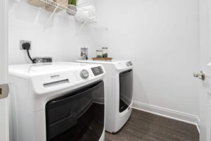 A laundry room with a large shelf, hardwood-style flooring, a washer, and a dryer.