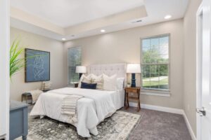 Primary bedroom in a 3 bedroom cottage with two tall windows, recessed lighting, and a coffered ceiling.