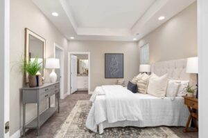 Primary bedroom in a 3 bedroom cottage with recessed lighting, a coffered ceiling, and access to a connected bathroom.