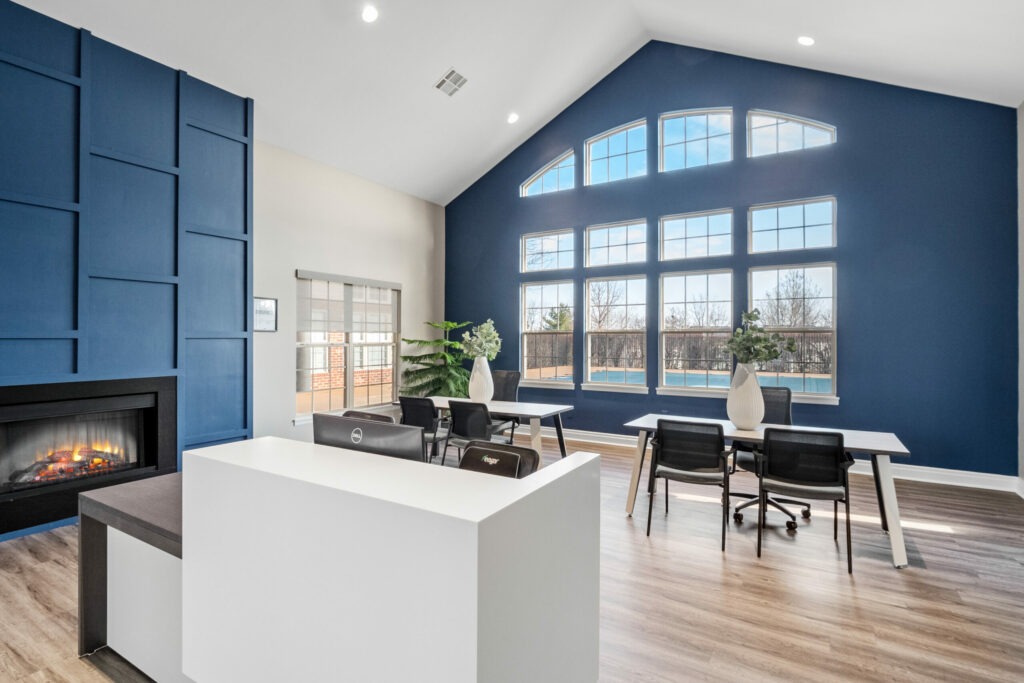 The Waterways of Lake Saint Louis' reception area with a collaborative workspace, fireplace, and view of the swimming pool.